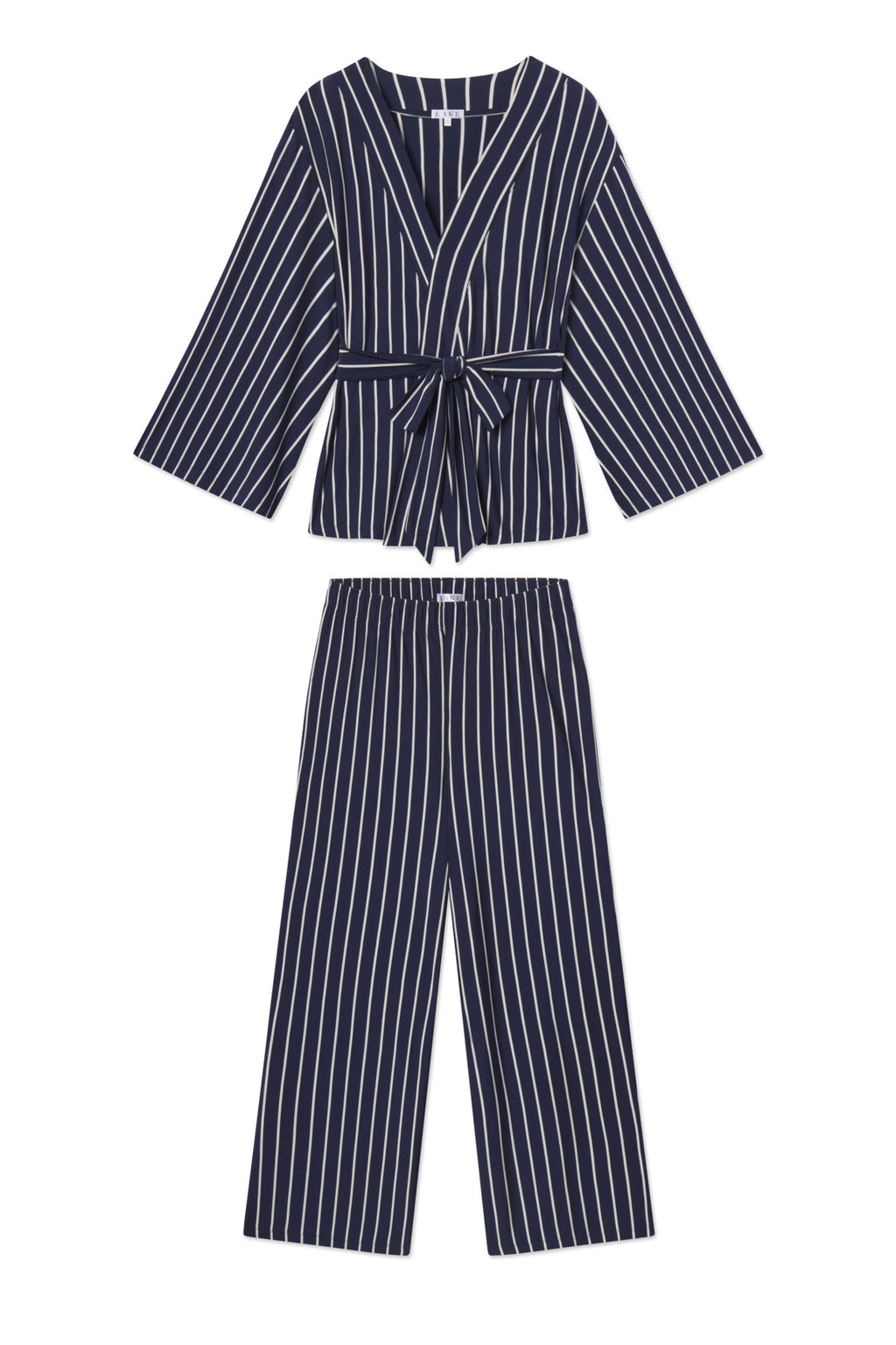 The DreamModal Kimono Pajama Set in English Navy Vertical Stripe features a long-sleeve, V-neck wrap top with a front tie and matching wide-leg pants in navy blue with white vertical stripes.
