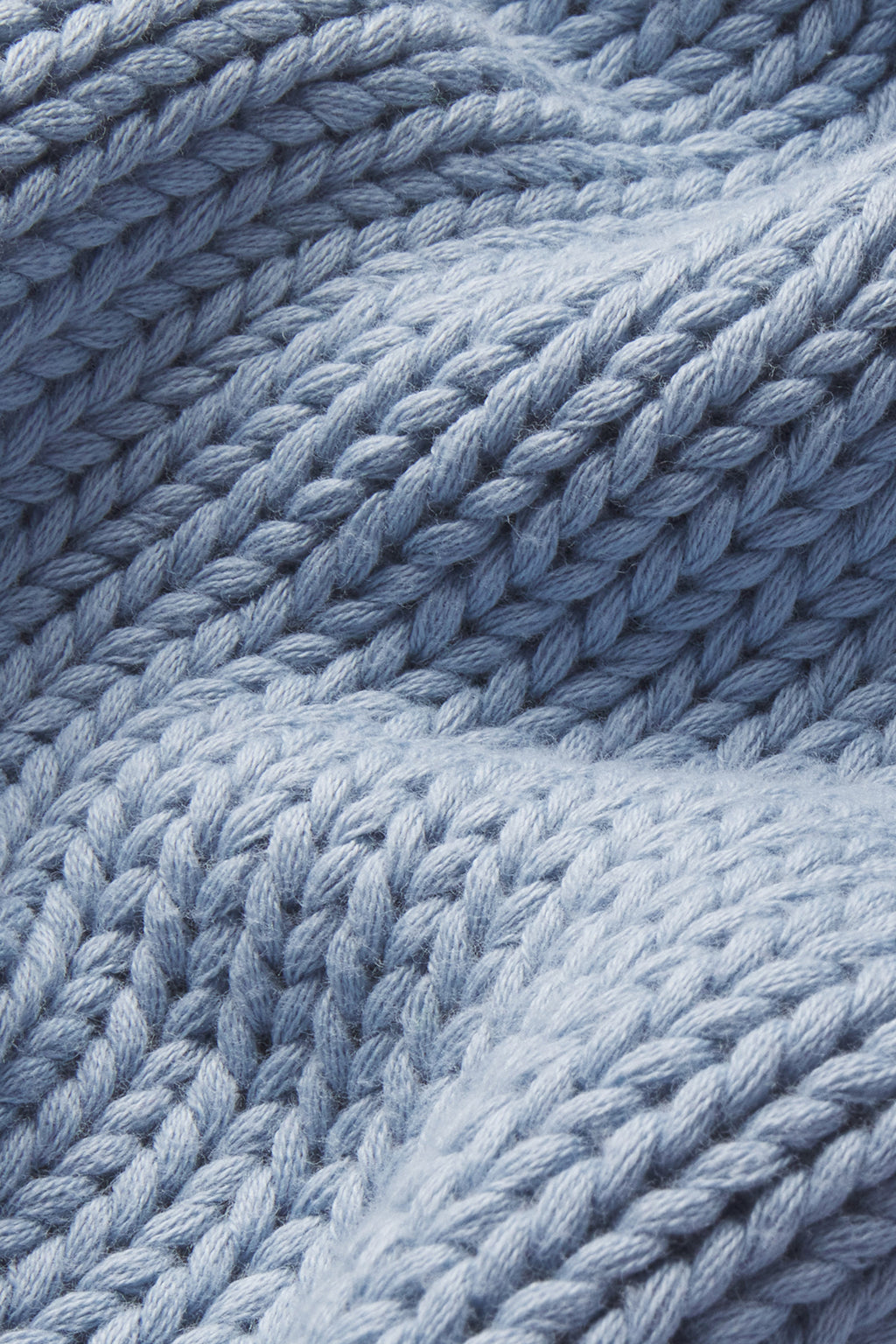 Close-up of chunky, textured Dusty Blue knit fabric with prominent loops and soft folds—perfect for the Jane Cotton Sweater in Dusty Blue, crafted from 100% cotton.