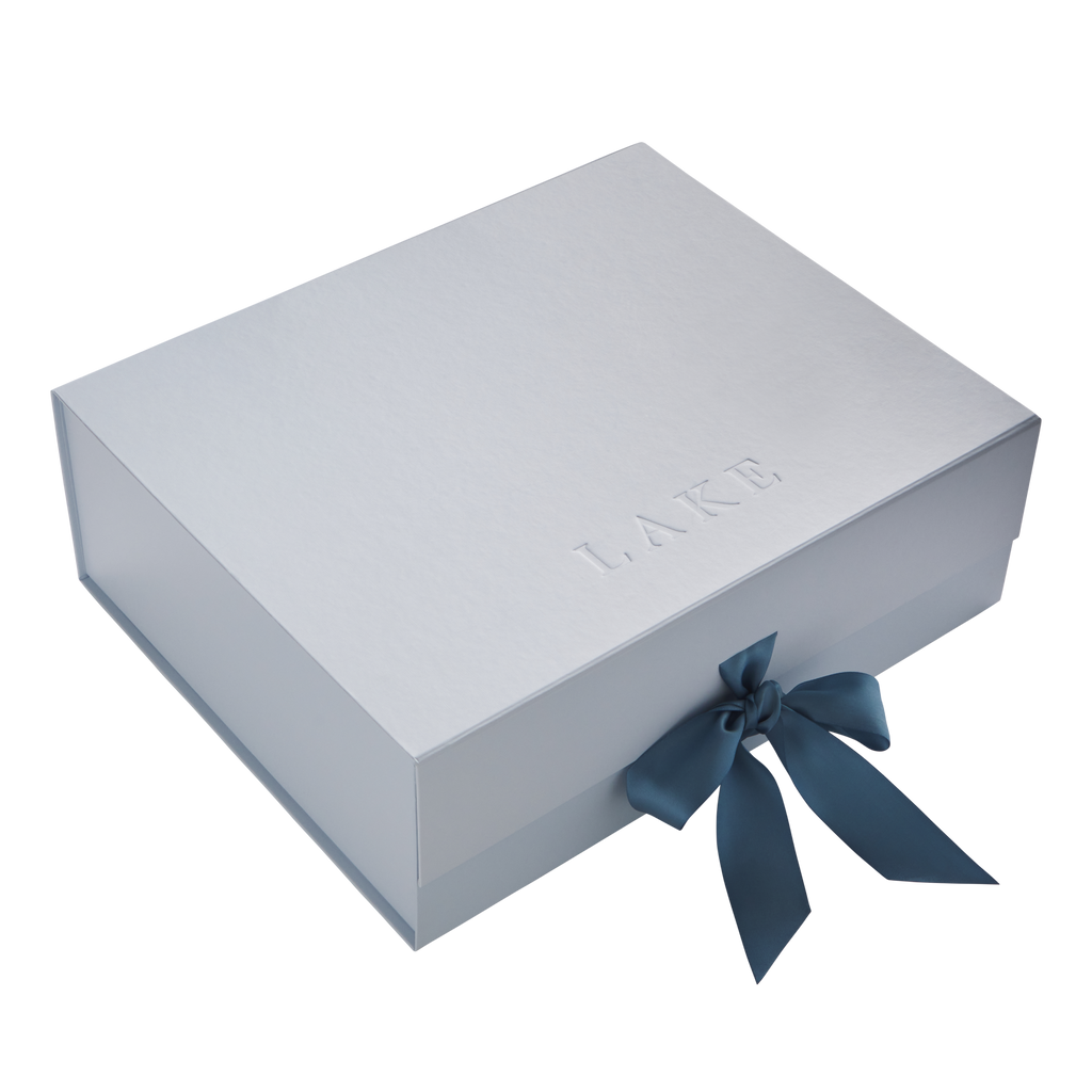 Light gray rigid box with embossed text and dark blue ribbon bow closure.
