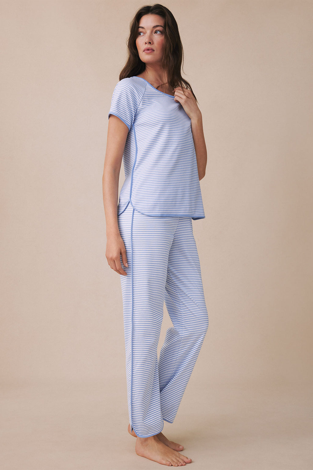 Woman wearing blue and white striped short-sleeve top and matching striped pants pajama set.