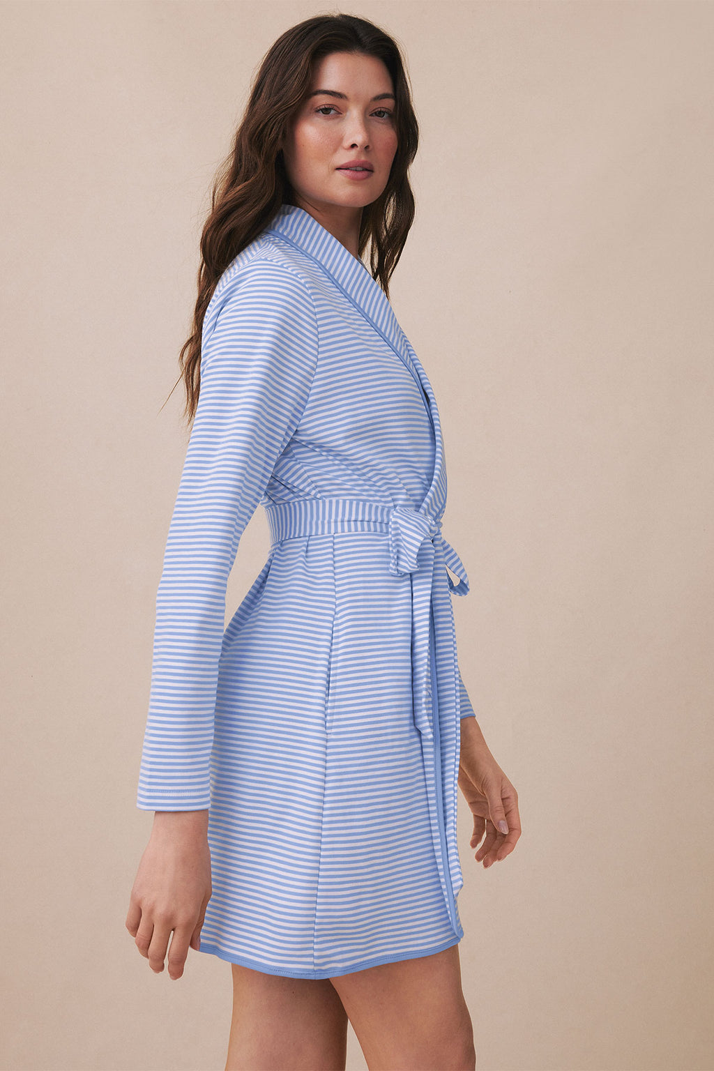 Woman wearing a blue and white striped short robe with three-quarter sleeves and a tie waist.