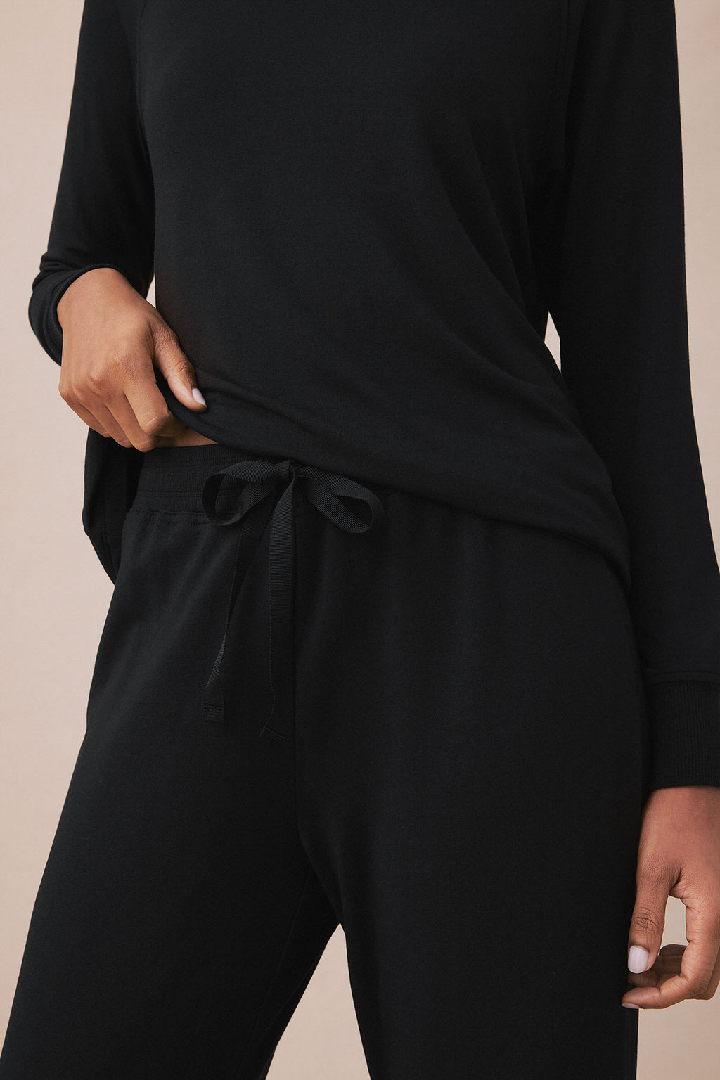 Black two-piece loungewear set with long-sleeve top and drawstring pants on model.