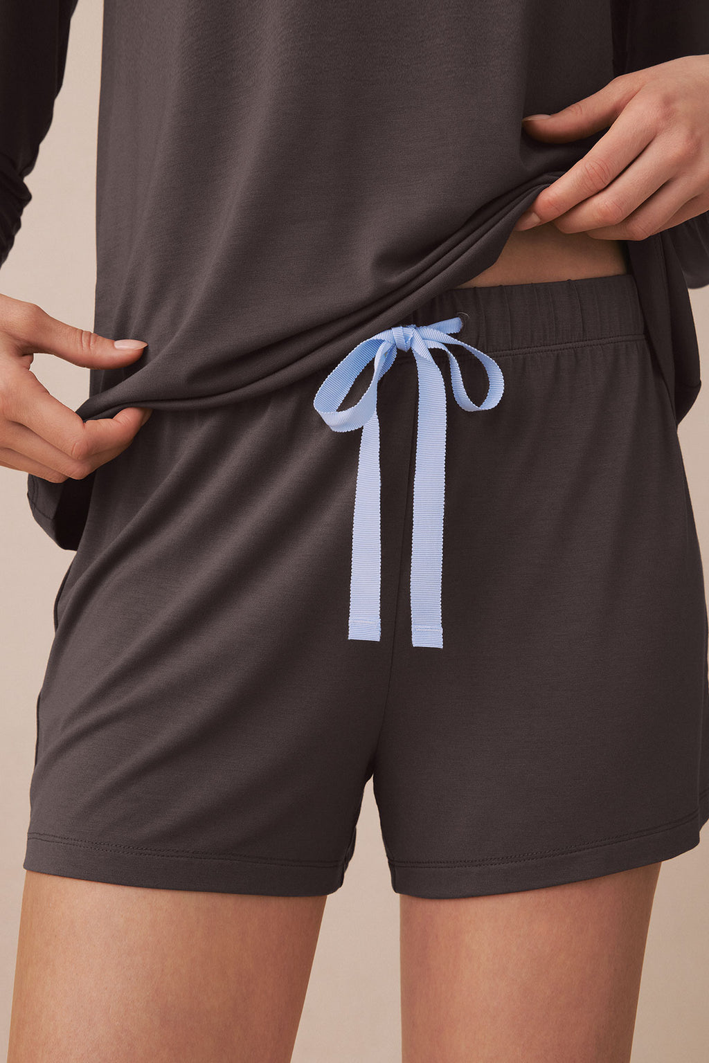 Charcoal shorts with blue ribbon drawstring tie at waistband, paired with matching long-sleeved top.