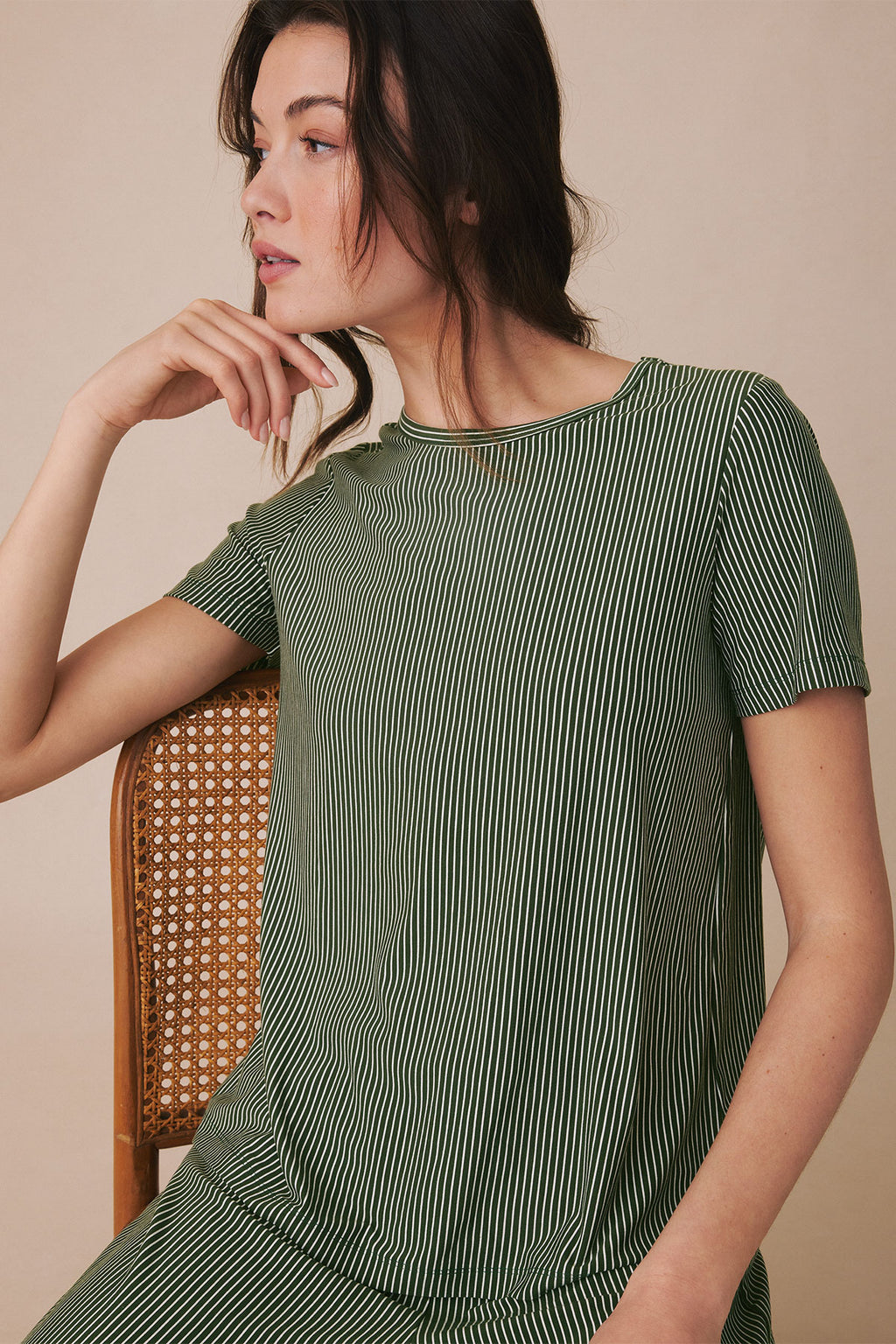 Woman wearing rosemary green short-sleeve top with vertical micro stripe pattern and cream ribbed trim.