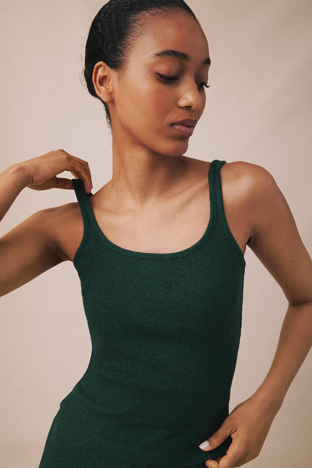 Woman wearing a dark green heather ribbed tank top with thin straps.