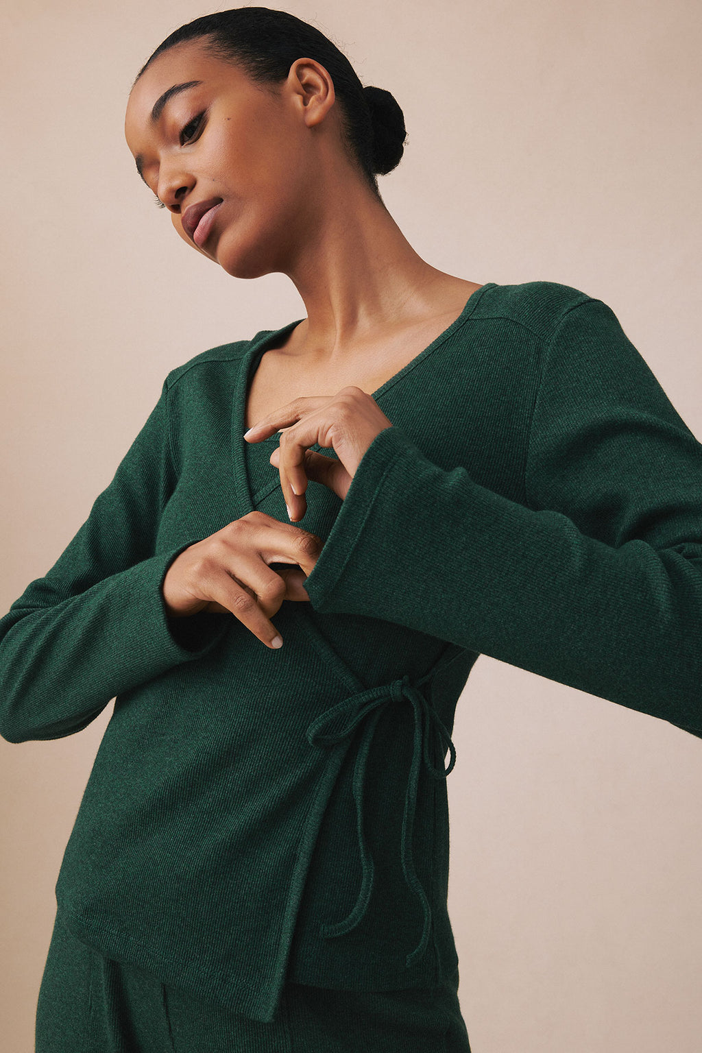 Woman wearing trekking green heather ribbed wrap top with drawstring waist detail.