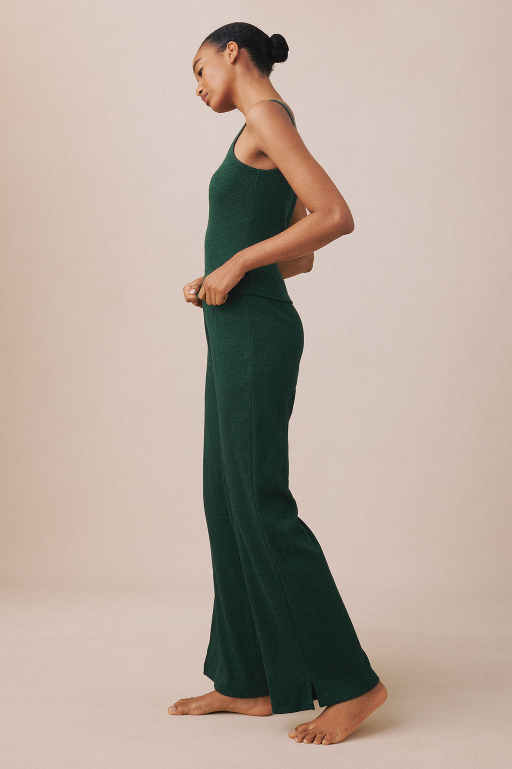 Woman wearing a trekking green heather ribbed tank top and matching flared pants, shown in profile view.