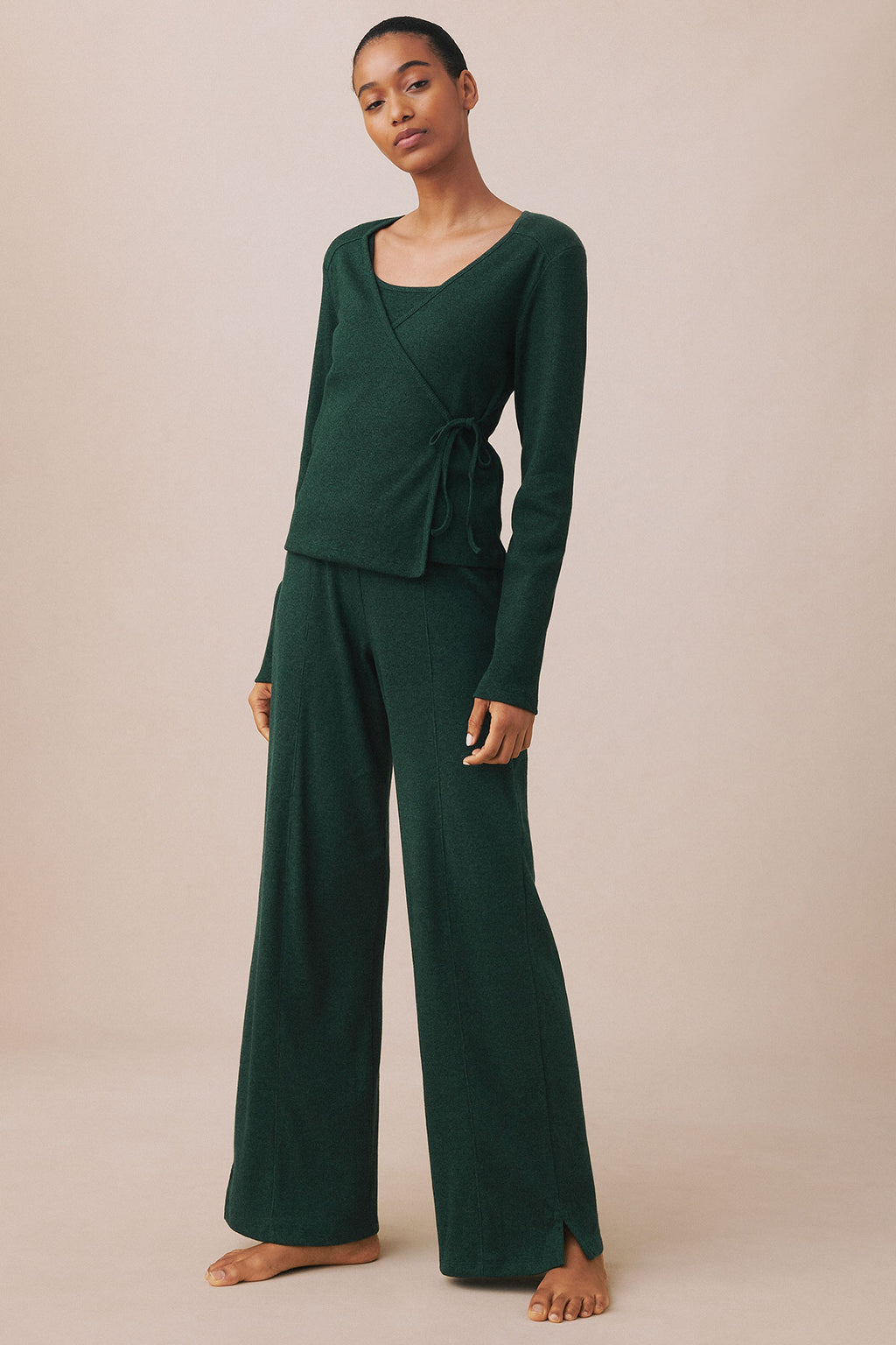 Woman wearing a three-piece set in dark green heather with a wrap top and wide-leg pants.