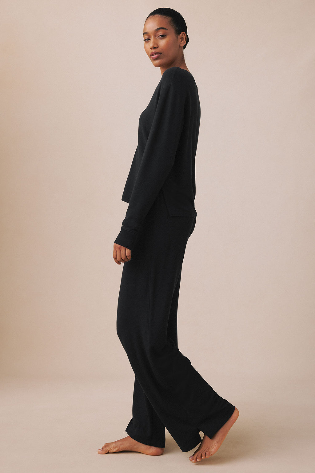 Black v-neck long-sleeve top and matching wide-leg pants on model shown from side profile.