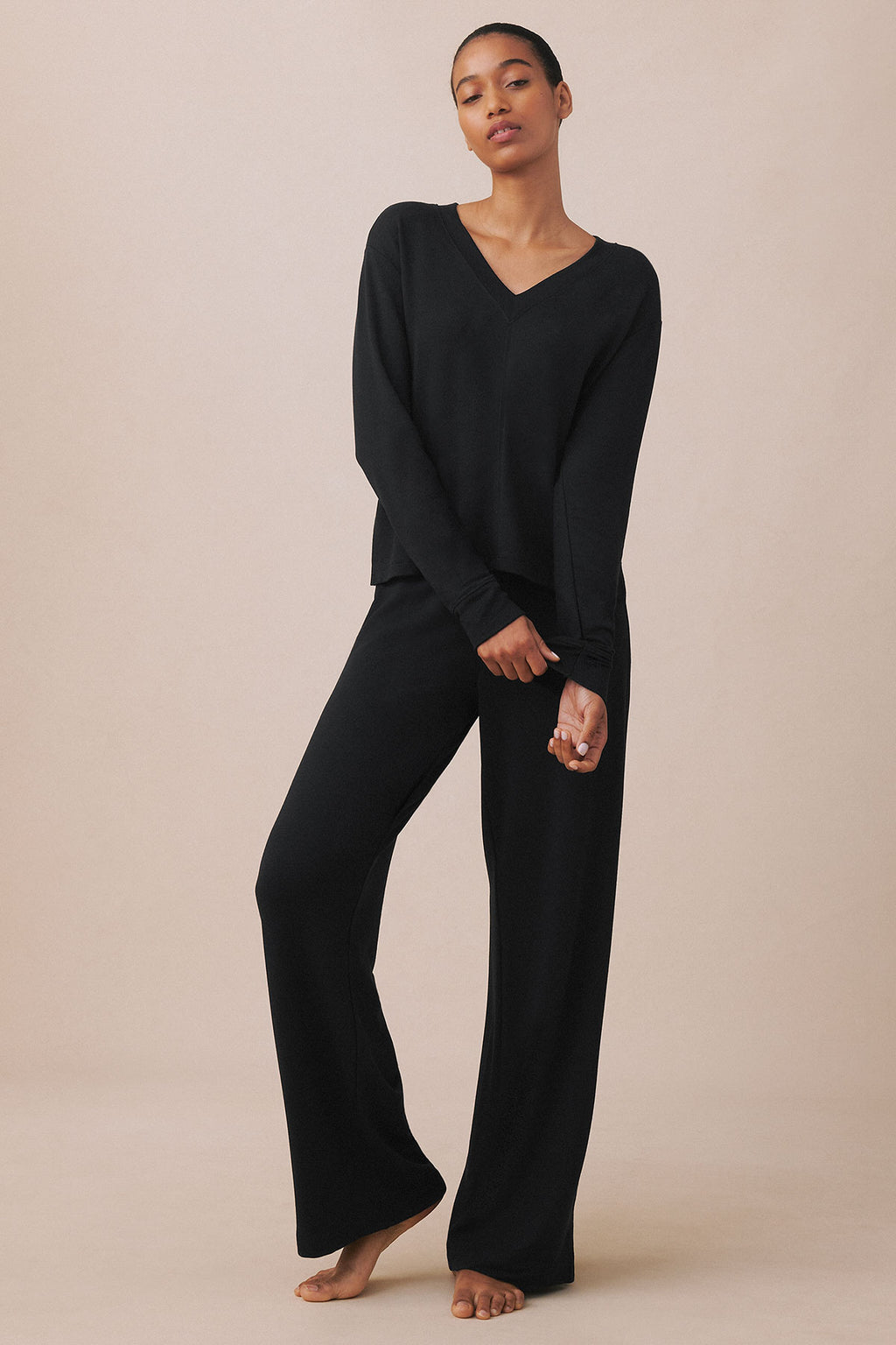Woman wearing black v-neck long-sleeve top and matching black wide-leg pants.