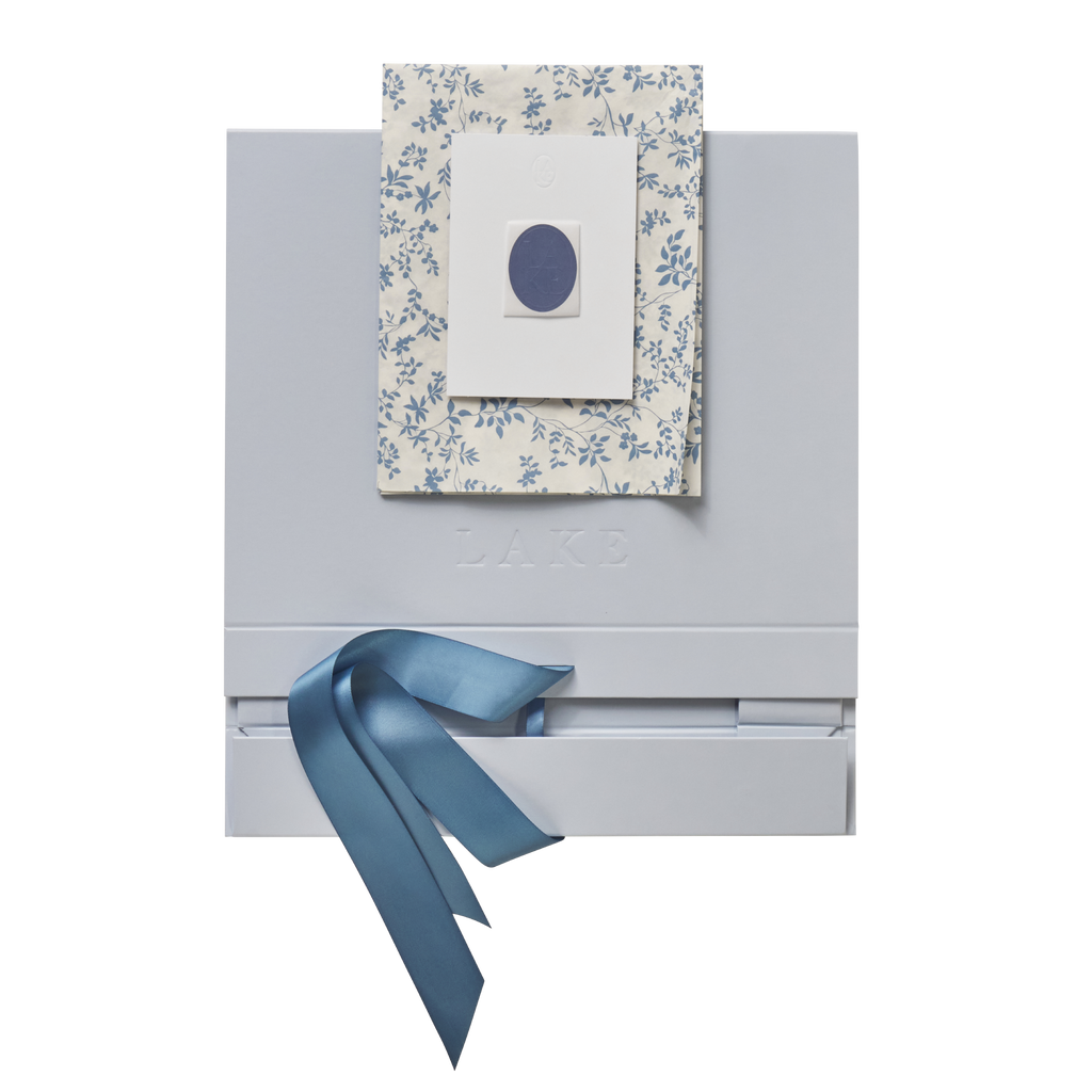 Flat-lay of white self-assemble box with blue floral patterned lid and blue ribbon bow.