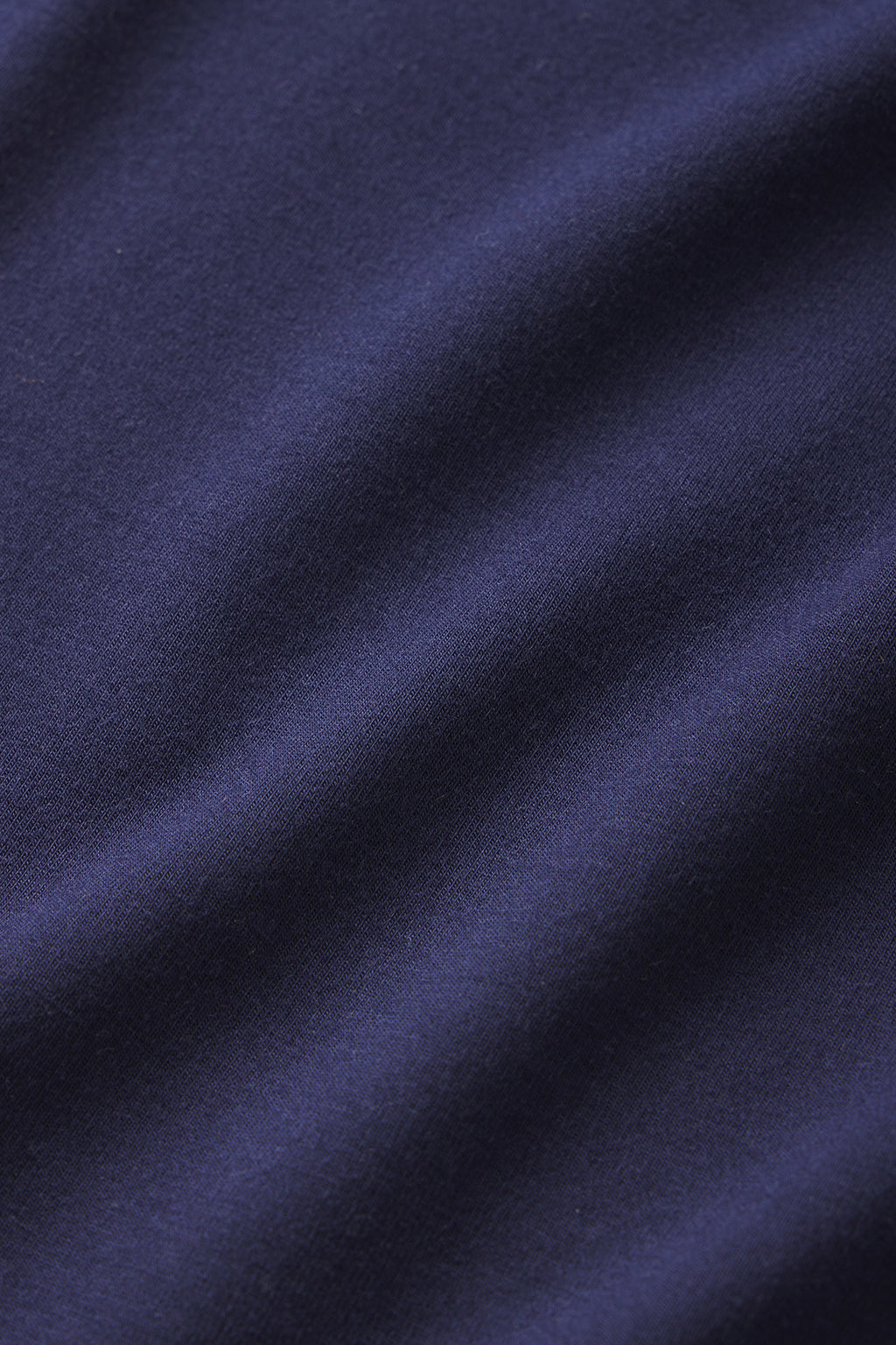 A close-up of dark blue modal fabric with smooth, soft folds running diagonally across the surface, reminiscent of the DreamModal Ribbon Tank-Long Set in English Navy.