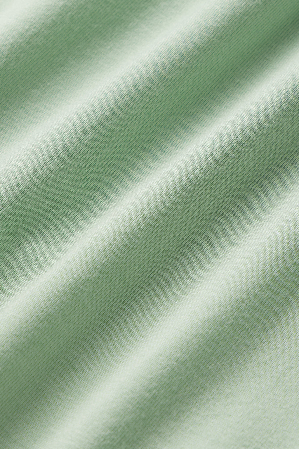 Close-up of the DreamModal Cami Pants Set in Parisian Green, showing soft folds and a smooth, slightly textured surface. Gentle shadows highlight the DreamModal fabric’s texture and subtle undulating pattern.