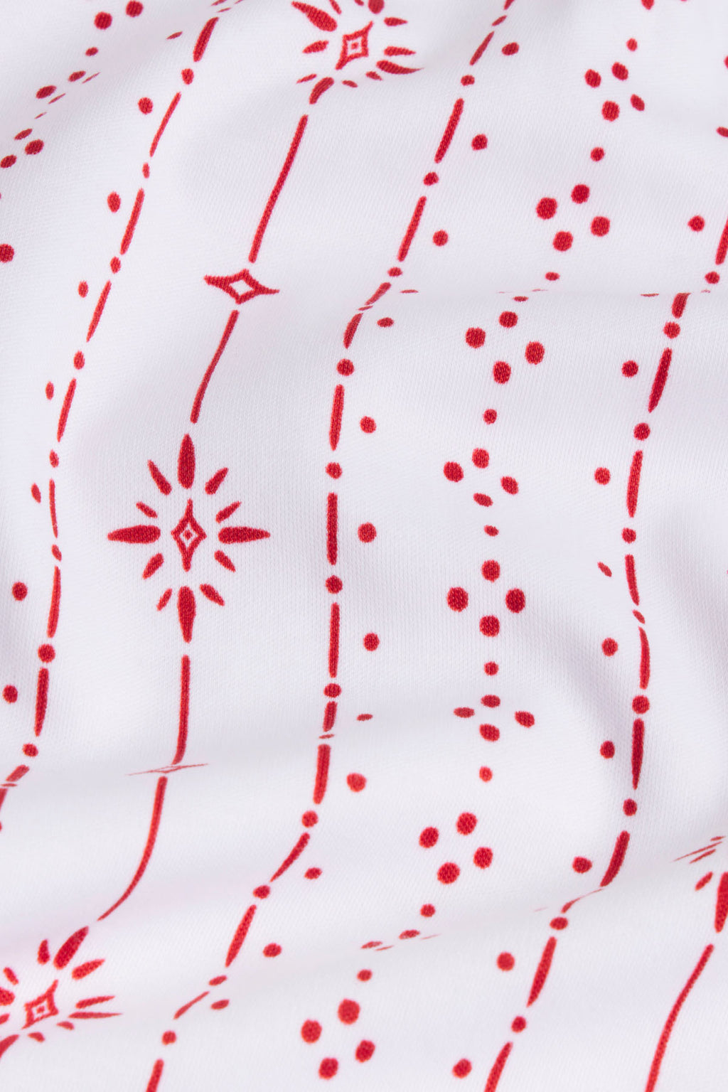 White fabric with red geometric stripe pattern featuring starburst and dot motifs throughout.