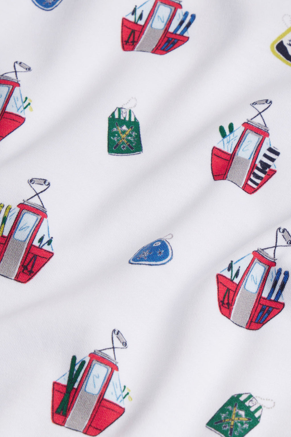 White fabric with embroidered ski lift cabins in red and gray, skis, snowboards, and green winter hats scattered throughout.