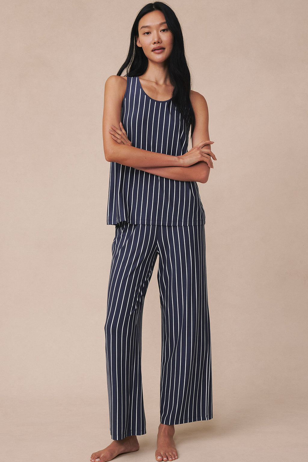 Woman wearing navy sleeveless tank top and matching wide-leg pants with white vertical stripes throughout.