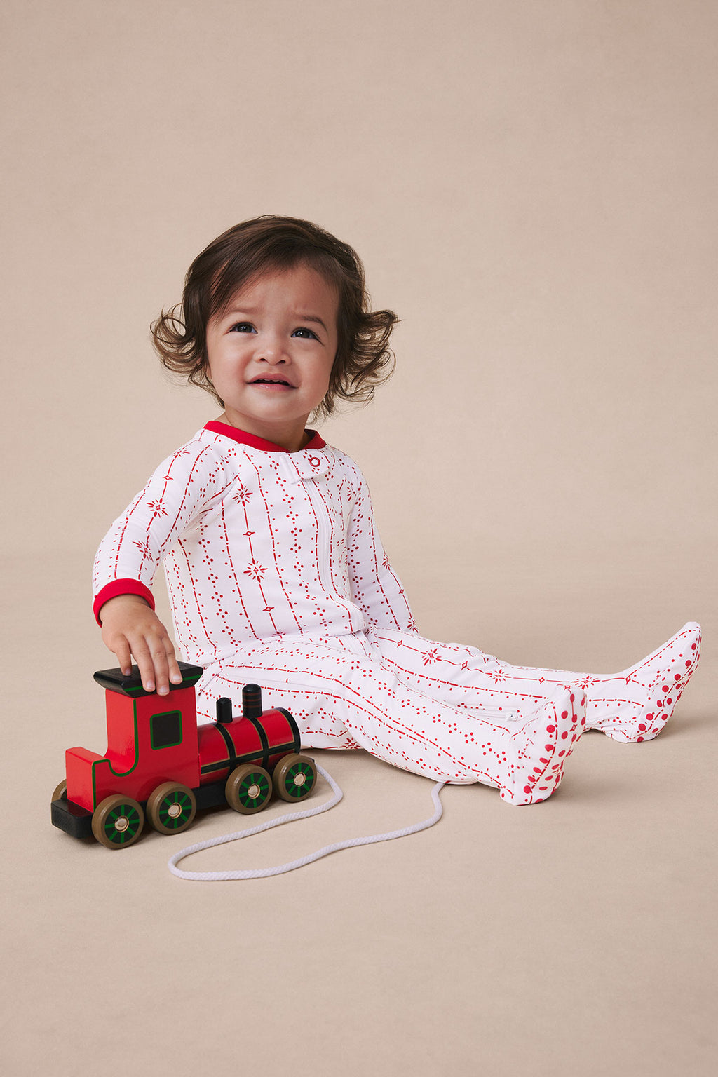 Toddler wearing red and white striped sleeper with small pattern, red cuff trim and matching feet.