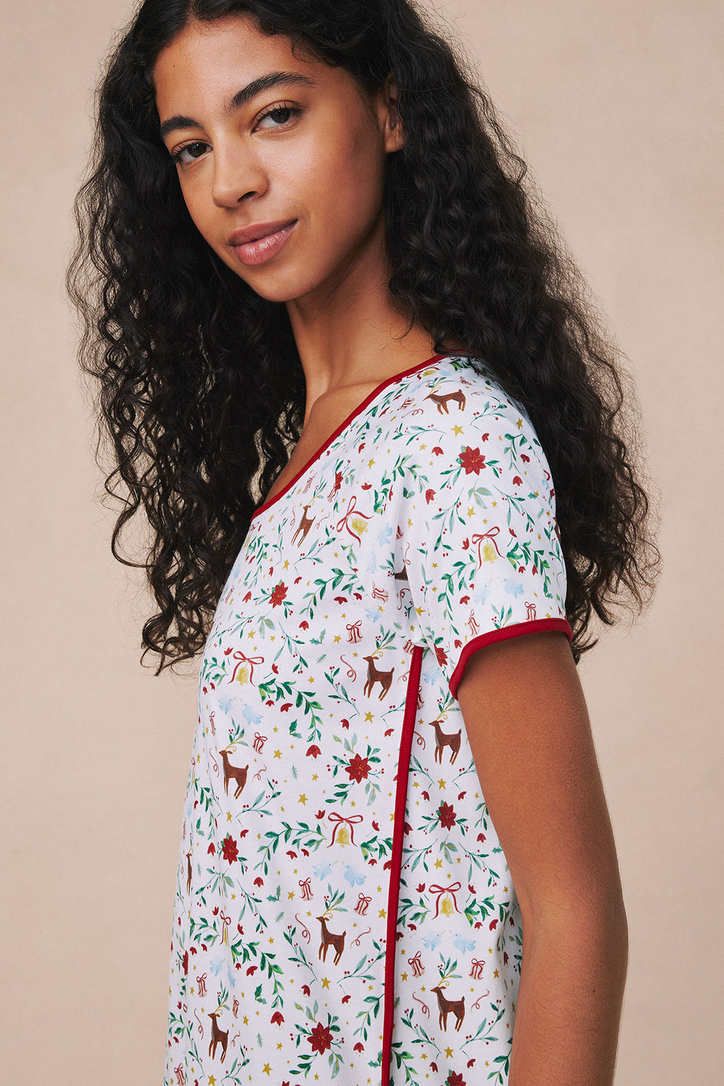 White Pima cotton nightgown with red trim featuring holiday-themed print of reindeer, flowers, and gift motifs.
