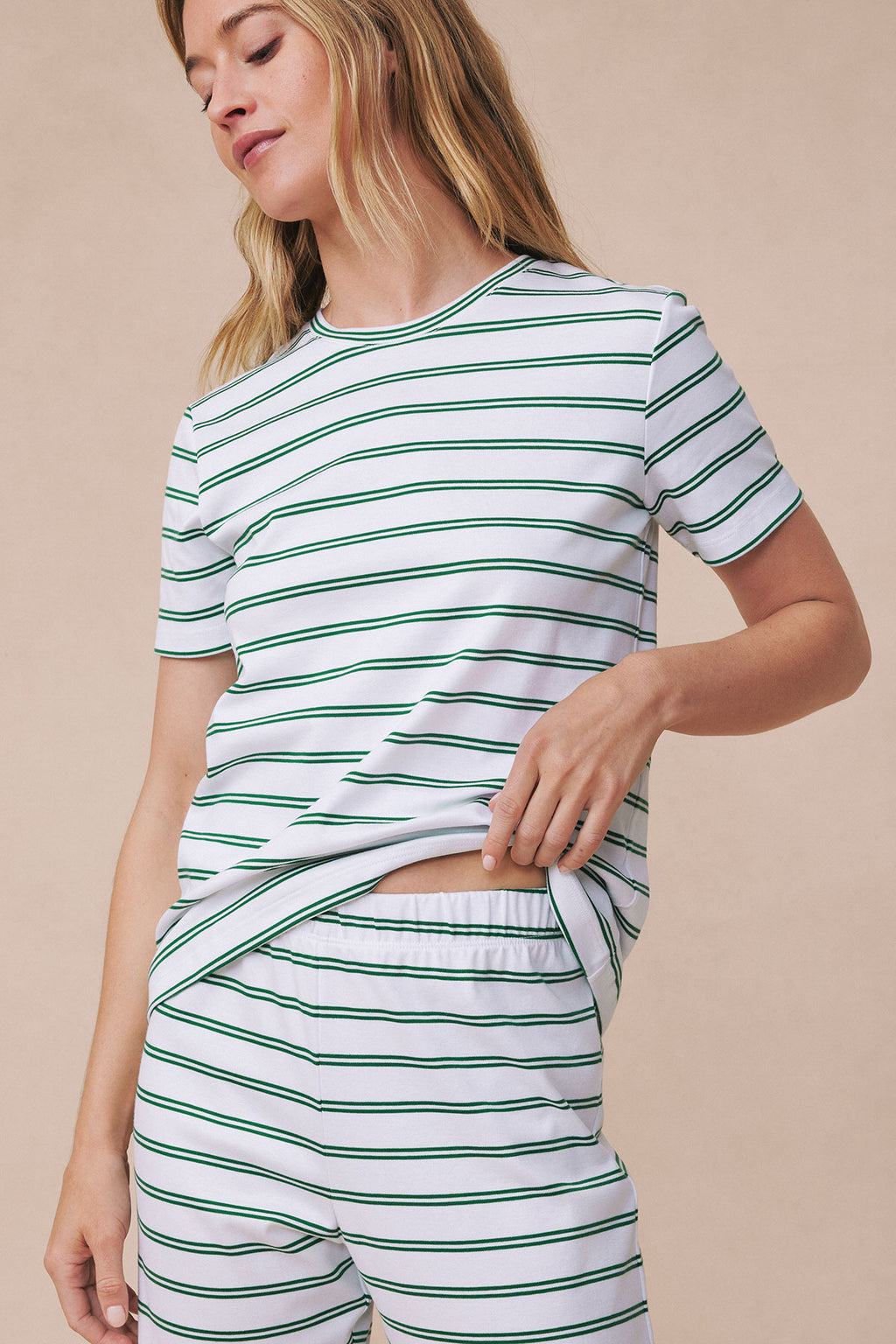 Woman wearing white short-sleeve crew neck top and matching shorts with green and navy horizontal stripes.