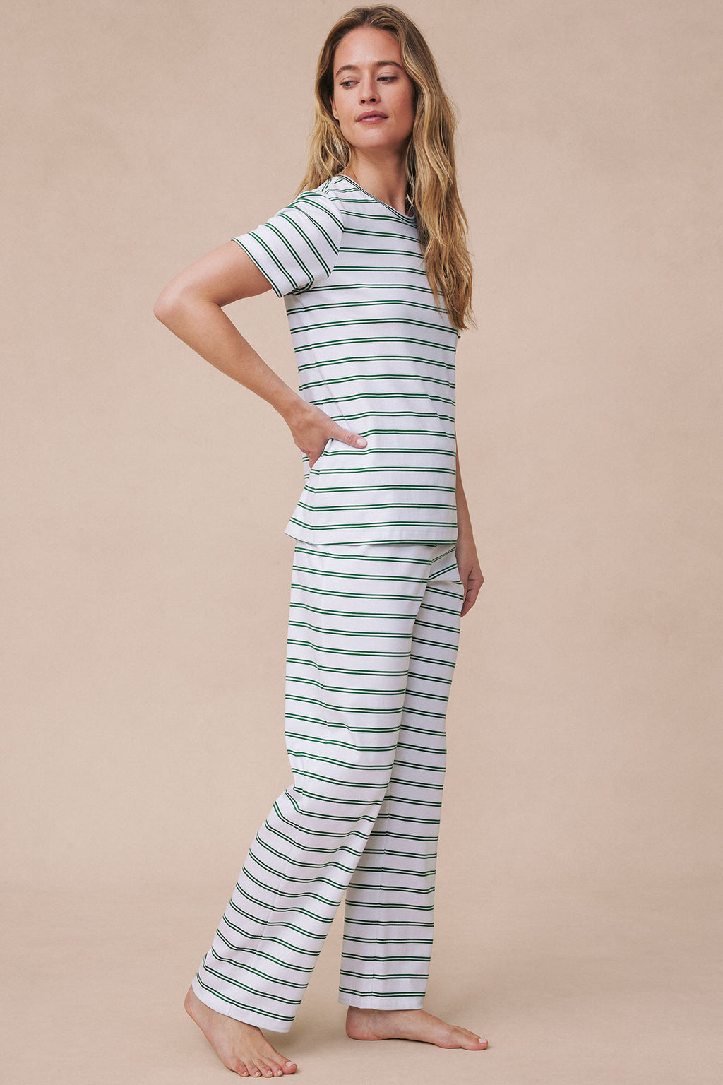Woman wearing white short-sleeved crew top and matching long pants with green and navy horizontal stripes.
