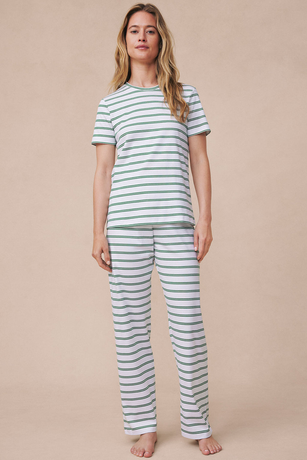 Woman wearing white short-sleeve crew neck shirt and matching long pants with green and navy horizontal stripes throughout.