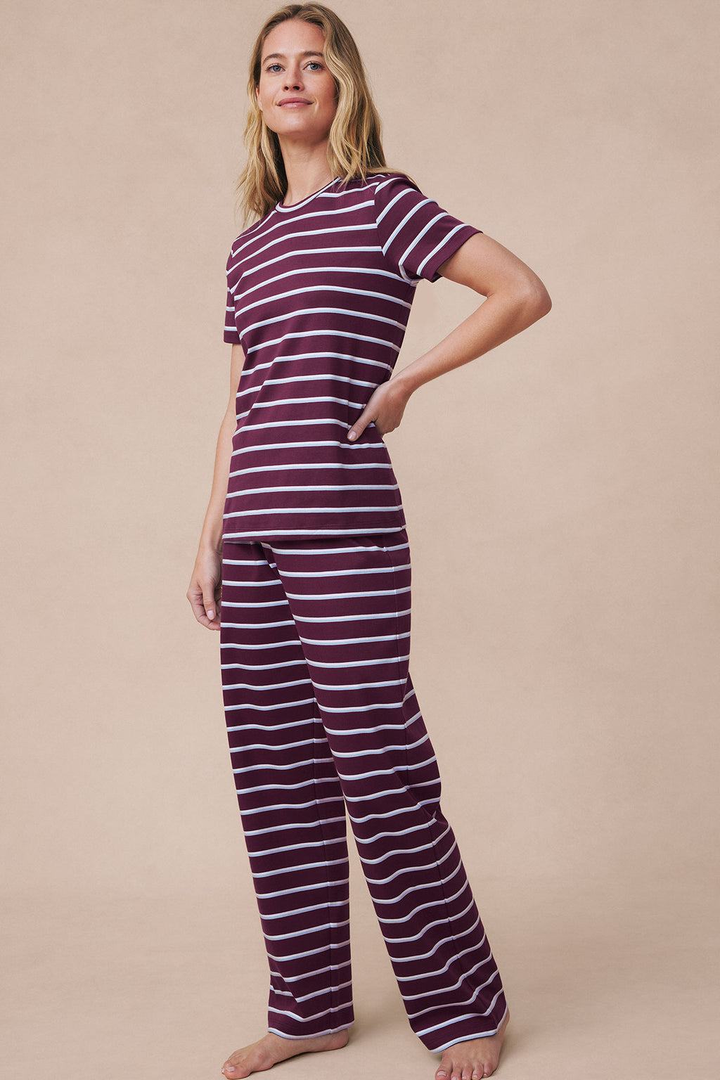 Woman wearing burgundy and white striped short-sleeve crew neck top paired with matching long pants.