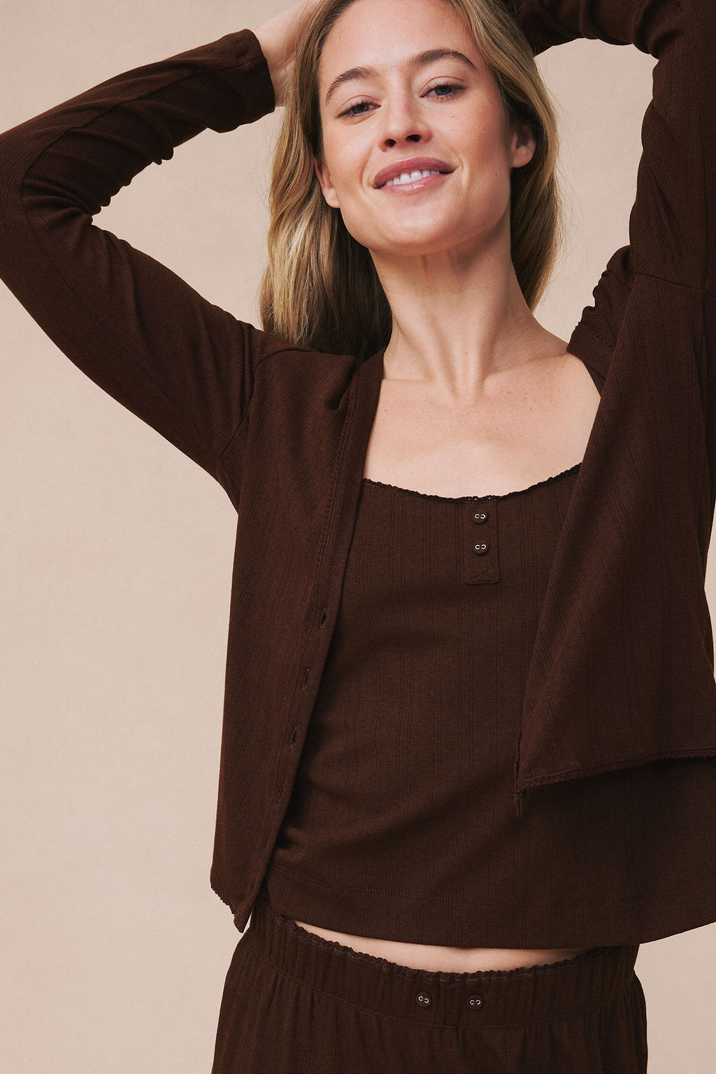 Woman wearing cocoa brown pointelle cardigan with matching ribbed top and pants.
