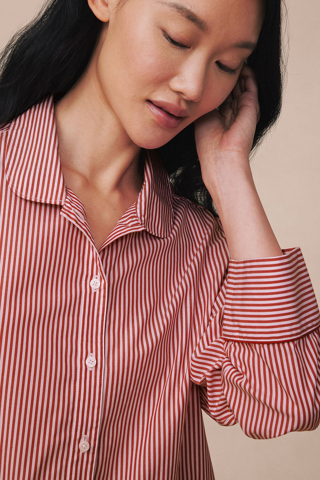Woman wearing red and white striped poplin pajama set with piped collar and long sleeves.