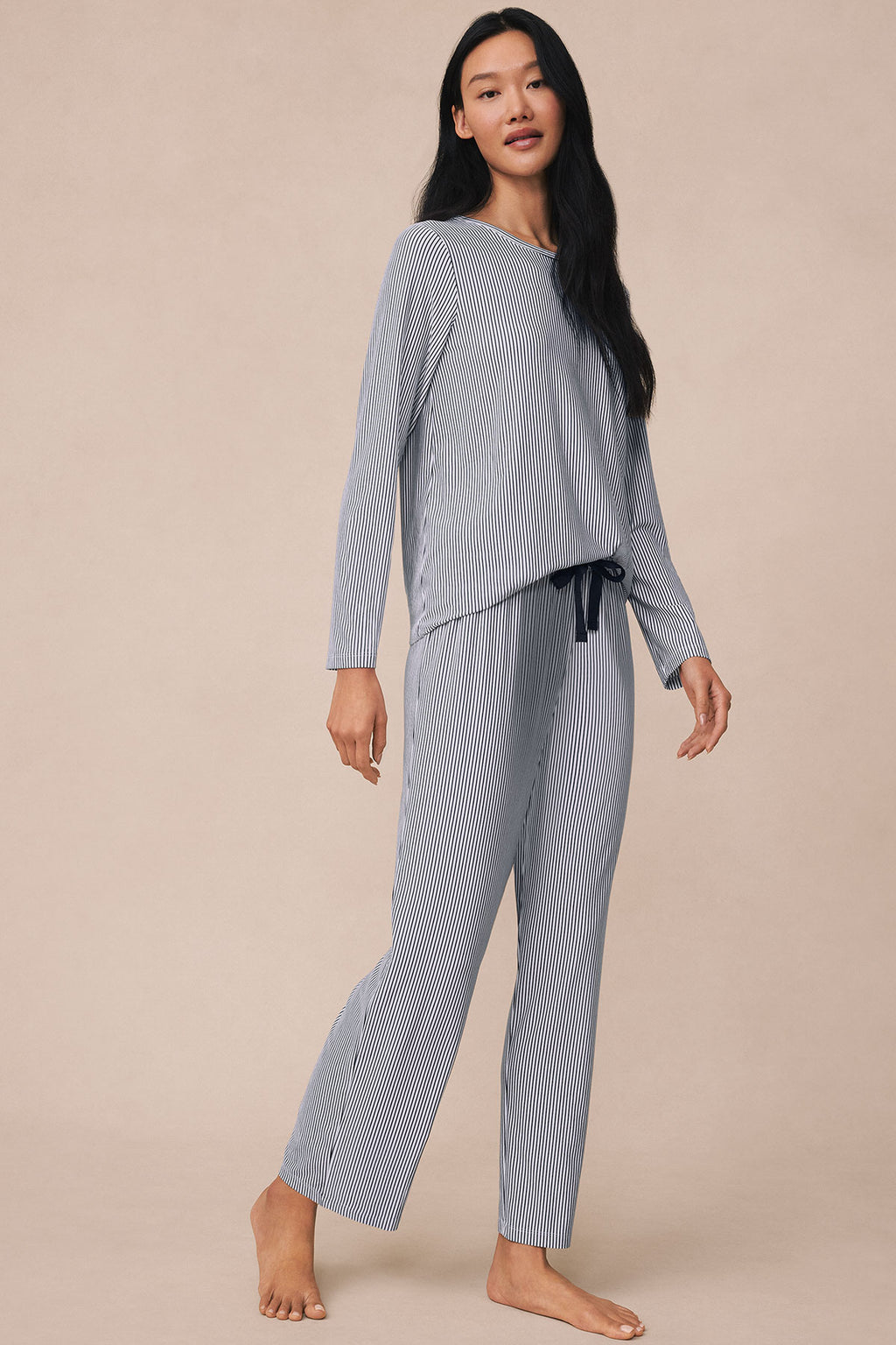 Woman wearing navy and white vertical striped long-sleeve top and matching pants with drawstring waist.