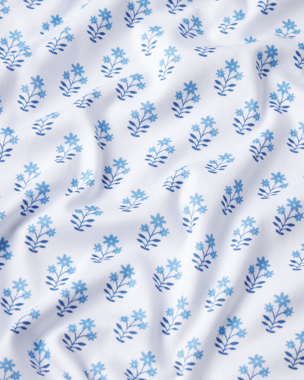 The Pima Nightgown in Serene Blue Posy is crafted from 100% Pima cotton and showcases a soft blue floral pattern, with gentle folds that add texture and dimension to the serene blue palette.