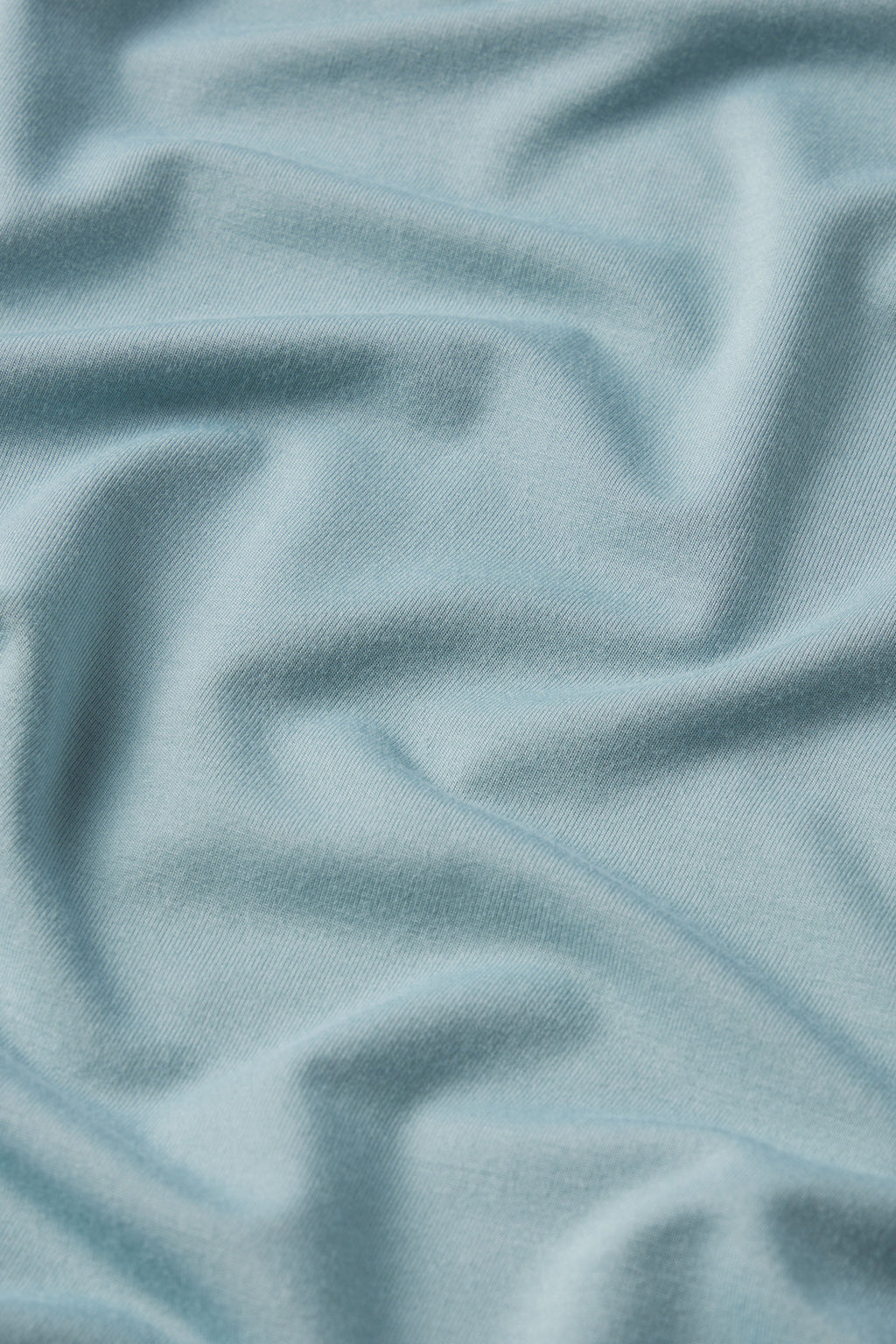Soft, stretchy knit fabric in stone blue with a smooth texture shown in gentle folds—perfect for the Men