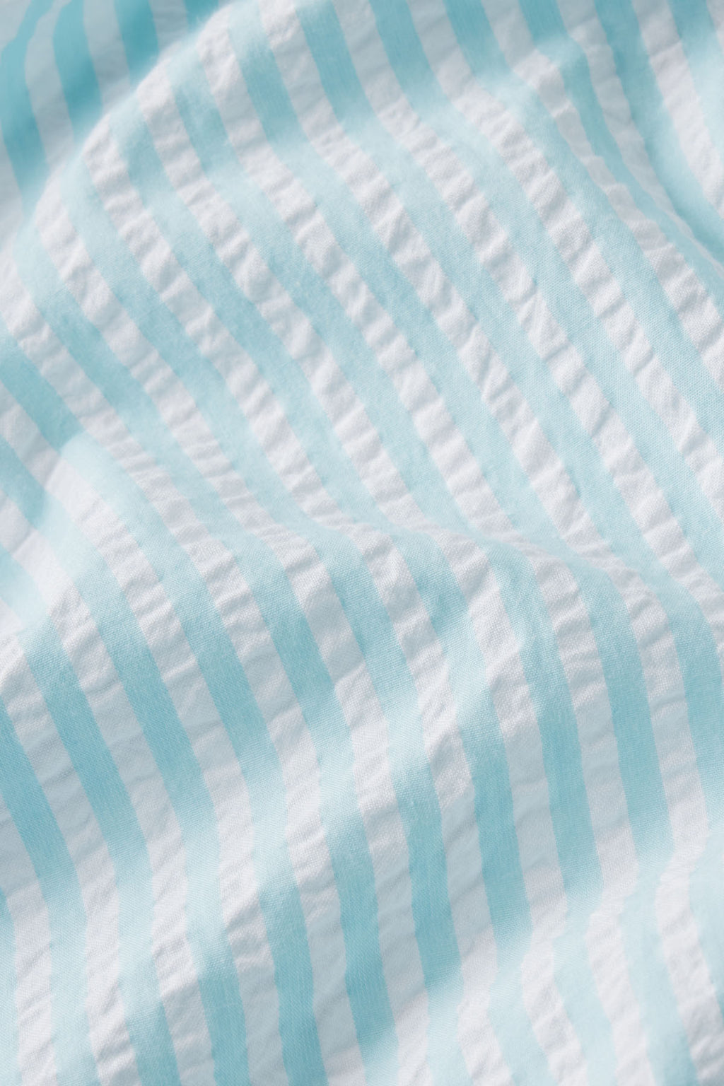 Close-up of the Alice Shorts Set in Salt Spray Seersucker, showcasing light blue and white crinkled fabric with soft texture and subtle shadowed folds.
