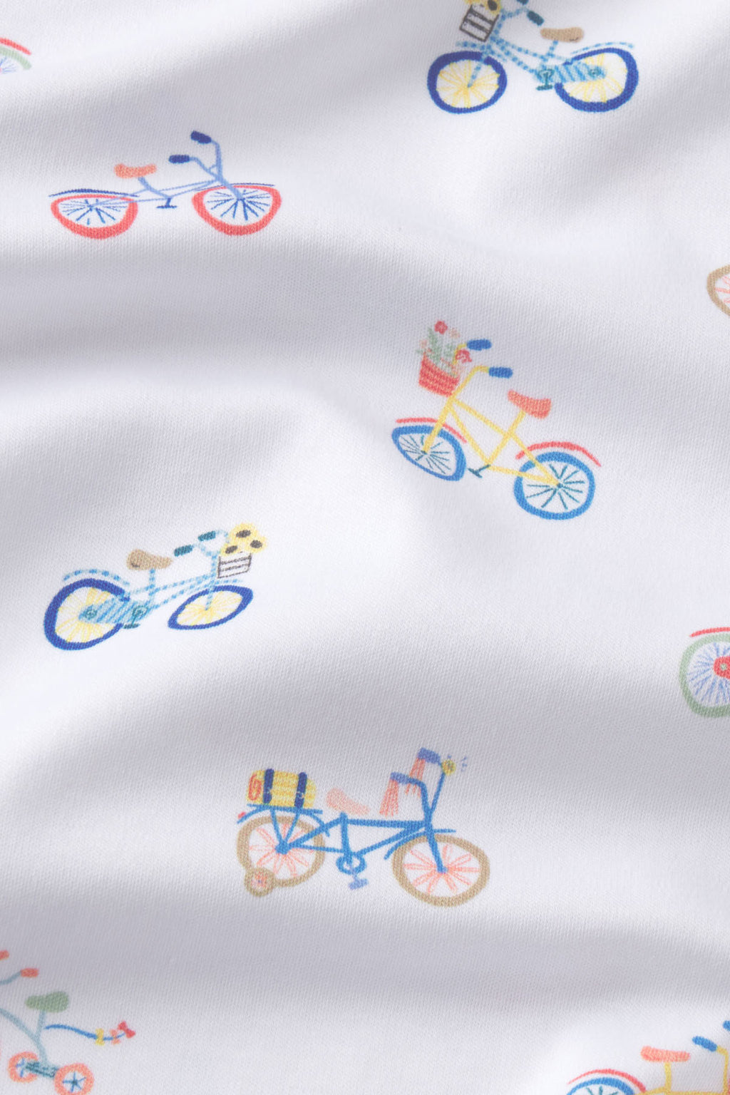 White fabric with colorful embroidered bicycles in red, blue, and yellow scattered throughout.