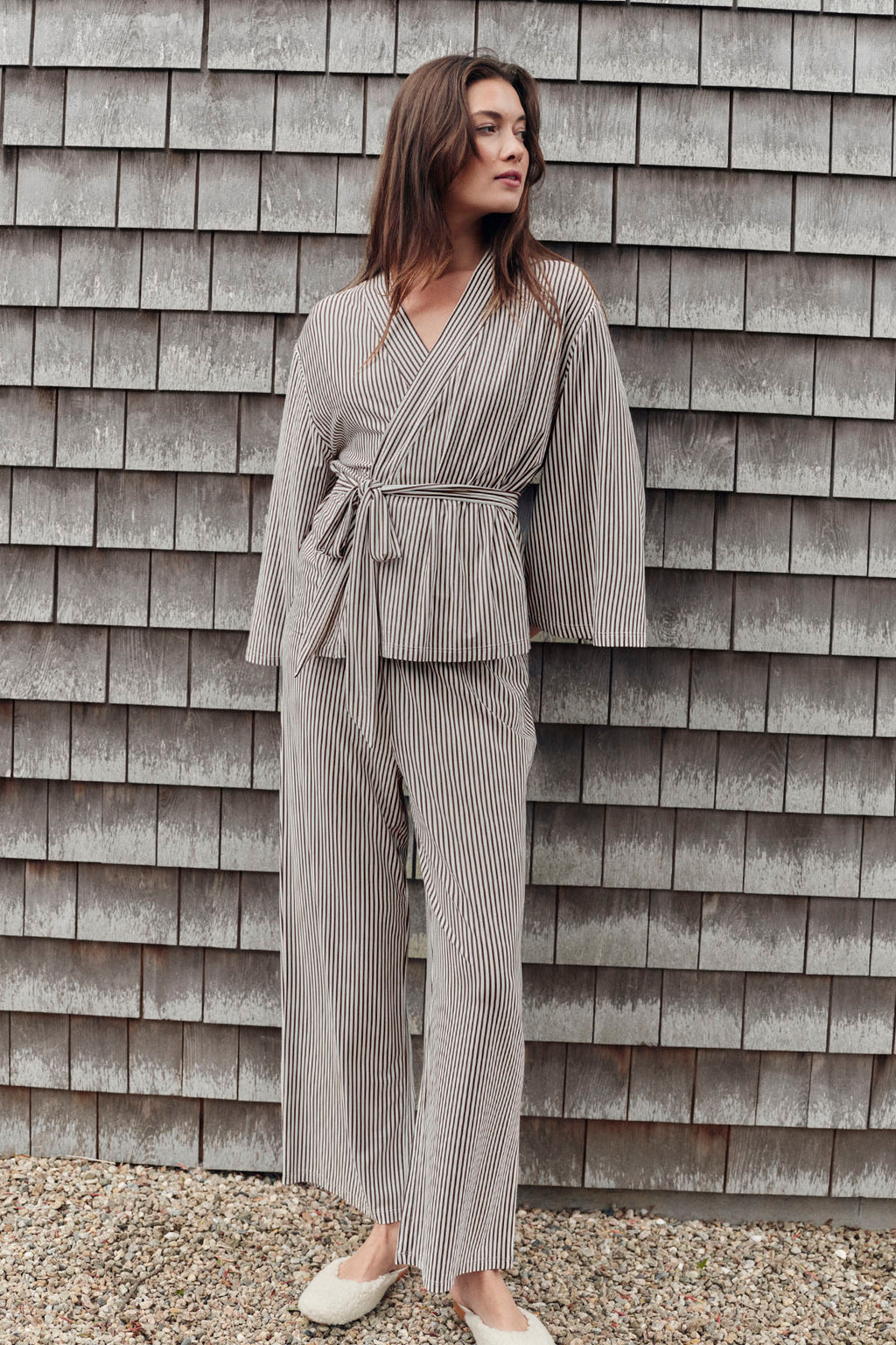 Woman wearing brown and white striped kimono pajama set with wrap top and matching pants.