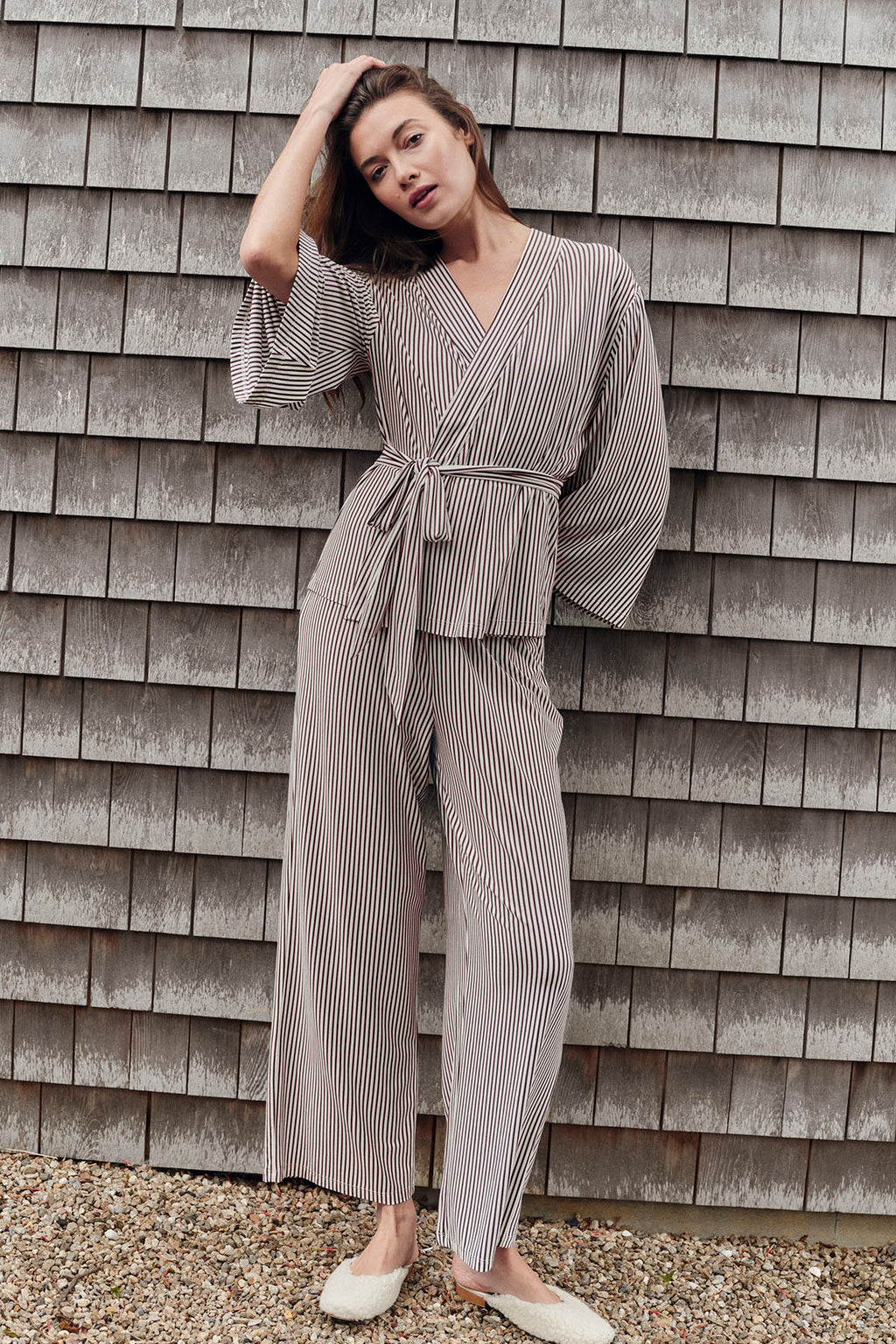 Woman wearing cocoa and cream vertical striped kimono pajama set with tie waist and full-length pants.
