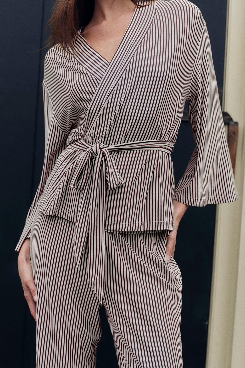 Brown and cream vertical striped kimono-style pajama set with wrap top and matching pants on model.