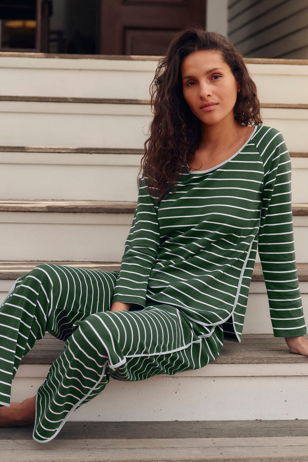 Green and white striped long-sleeve pajama set with crew neckline on seated model.