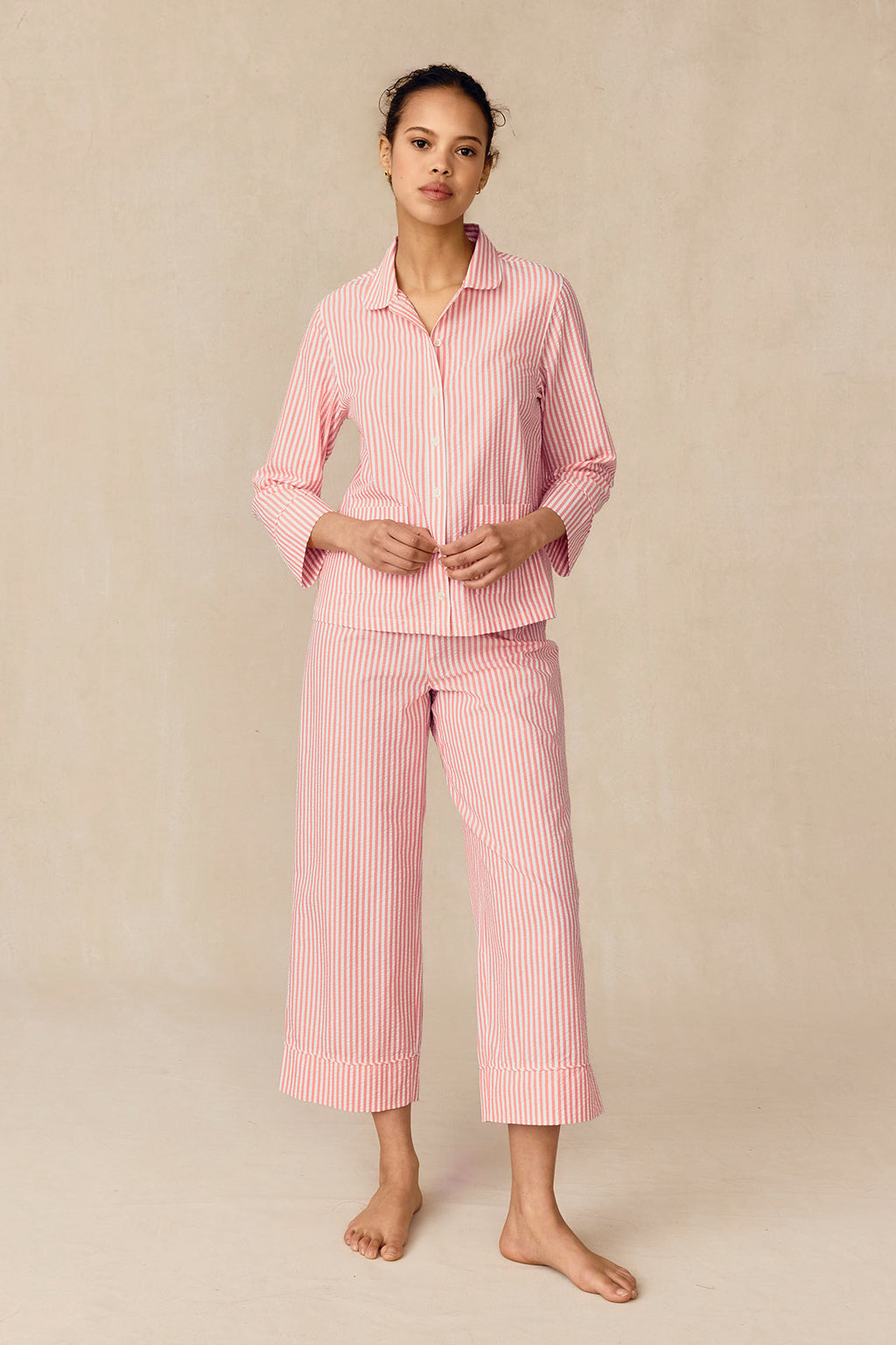 Woman wearing pink and white striped button-up shirt and matching cropped pants set.