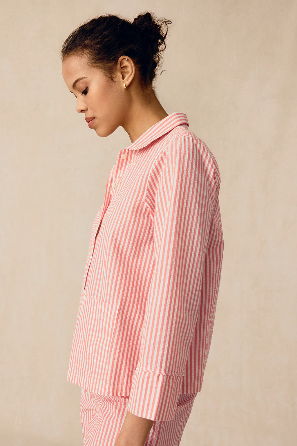 Woman wearing coral and white striped seersucker shirt and matching shorts in side profile.