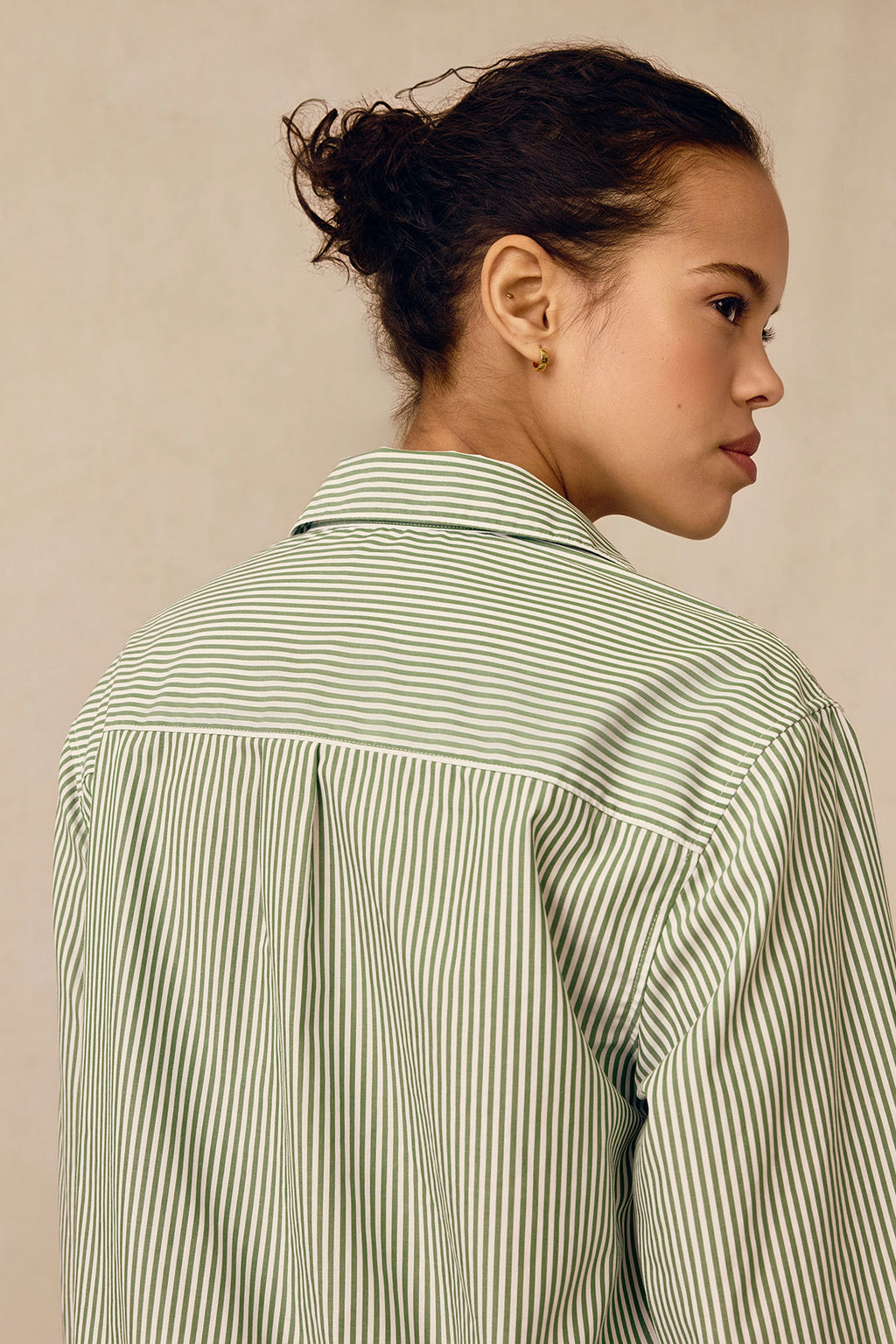 A woman with her hair in a bun, seen from behind and turned slightly to the side against a neutral background, wears the Poplin Piped Long-Long Set in Palm Riviera Stripe.